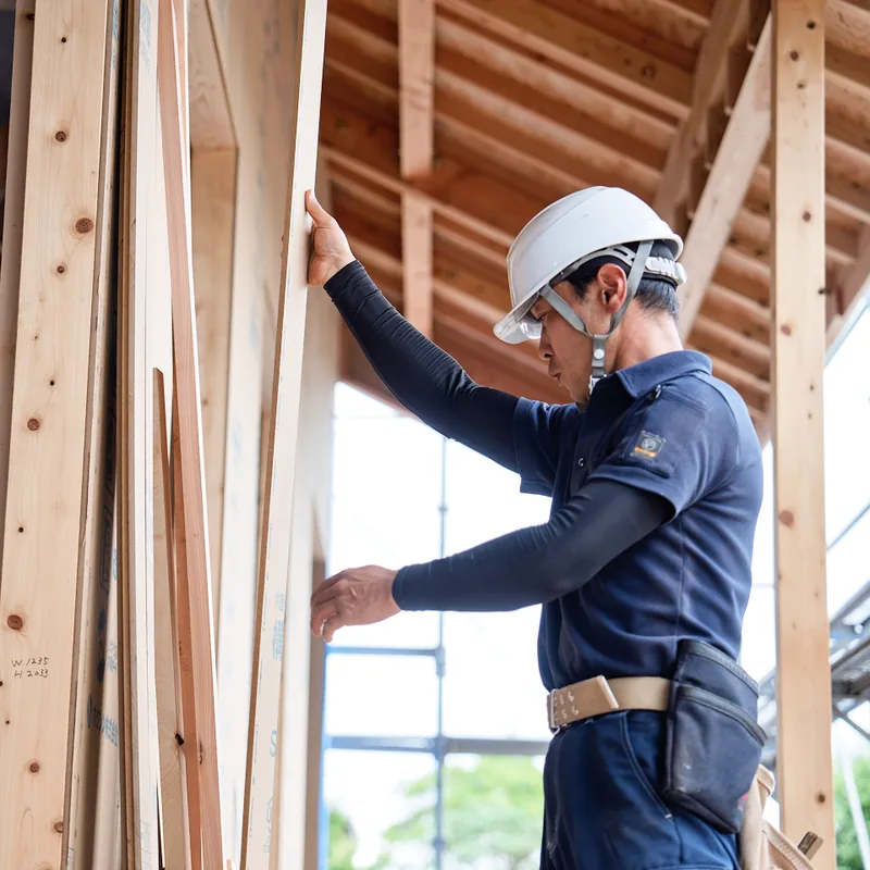 建方中の建物で材を支える大工