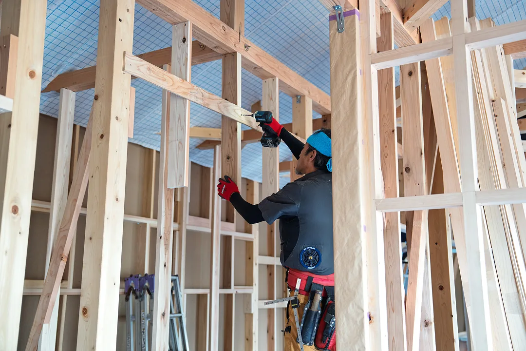 建て方中の躯体で、筋交いを取り付ける大工